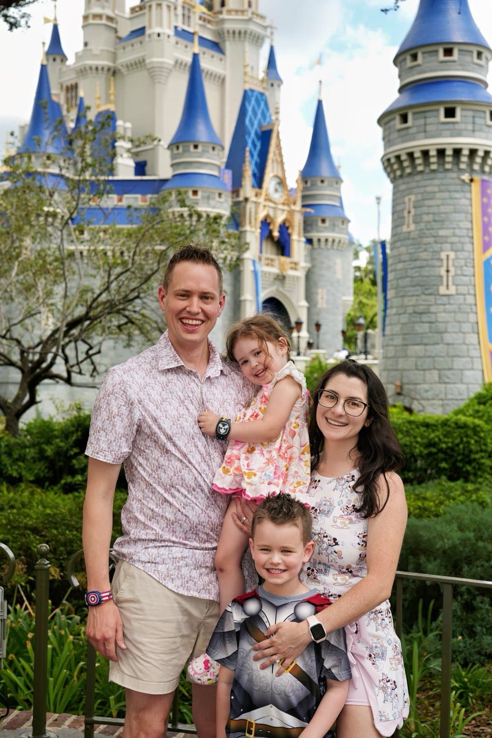 The Sampson family in front of a castle at a theme park, two parents with their two young children.
